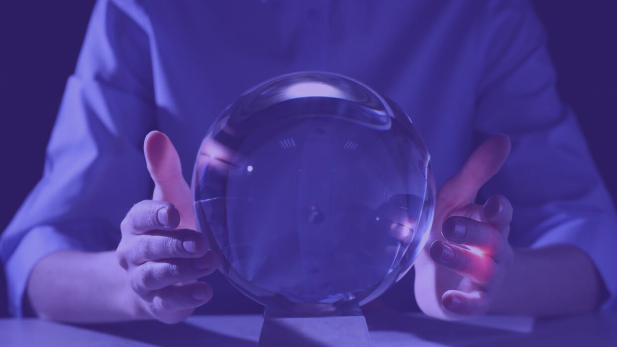 A person holding a crystal ball with both hands, set against a purple background. The ball is clear and reflects light, suggesting themes of mysticism or prediction.