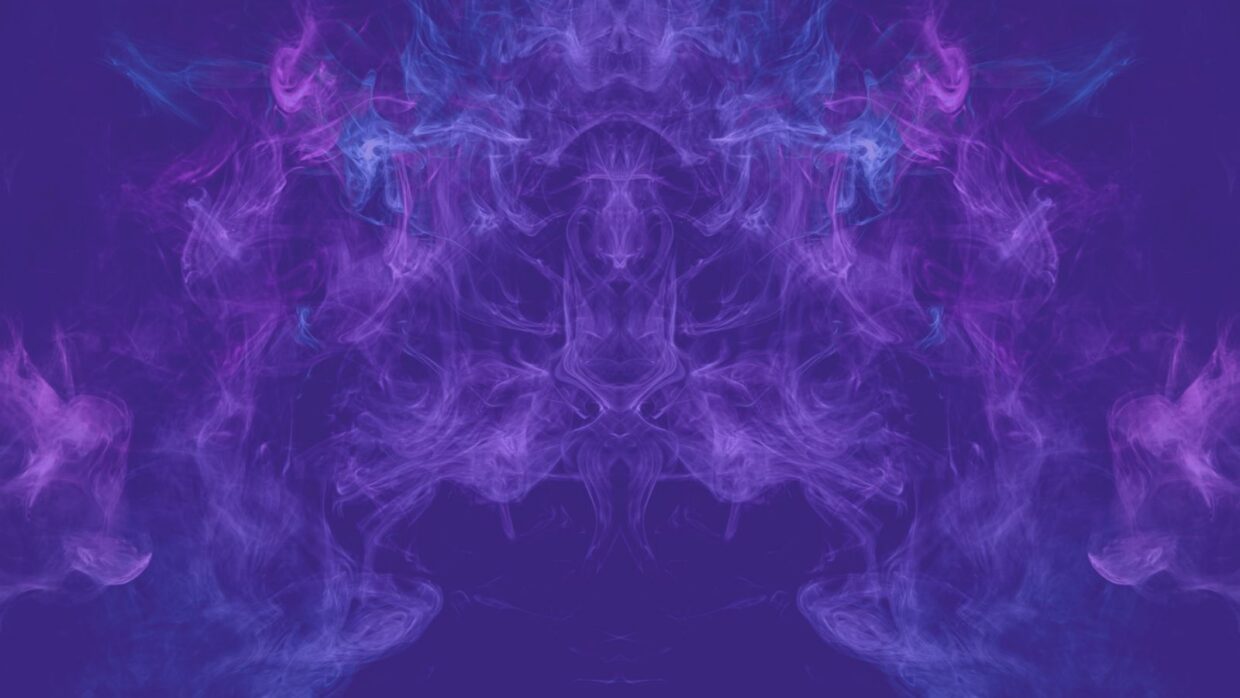 An abstract image featuring swirling clouds of purple and blue smoke on a dark background, creating a symmetrical pattern.